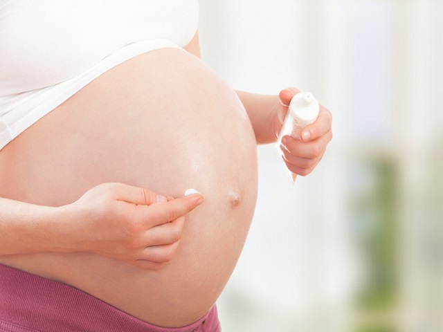 belly of pregnant woman  and moisturizing cream